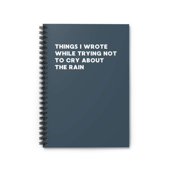 Spiral notebook titled 'Things I Wrote While Trying Not to Cry About the Rain' with a dark cover.