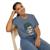 Smiling woman wearing a Hipster Squatch T-shirt featuring Sasquatch in a beanie and glasses, sitting on a chair.