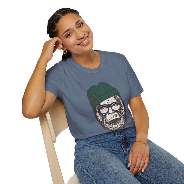 Smiling woman wearing a Hipster Squatch T-shirt featuring Sasquatch in a beanie and glasses, sitting on a chair.