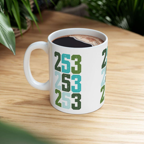 Two-Five-Three Pop Tacoma ceramic mug featuring stacked area code design in vibrant colors on wooden table.