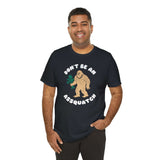 Man wearing Don’t Be an Assquatch Tee with friendly Bigfoot design holding flowers.