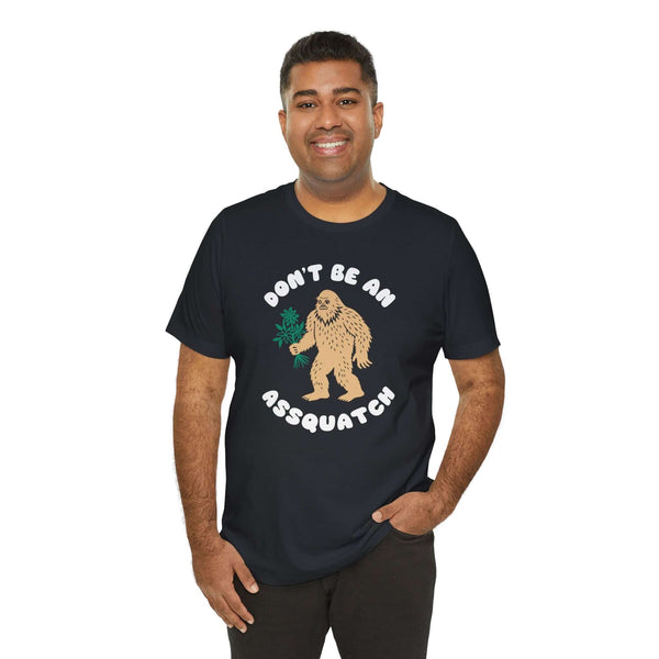 Man wearing Don’t Be an Assquatch Tee with friendly Bigfoot design holding flowers.