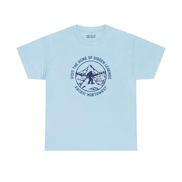 Blue t-shirt featuring a Bigfoot design with "Visit the Home of Hidden Legends" text, perfect for fans of Northwest folklore.