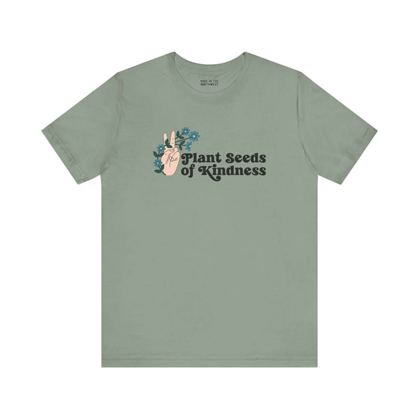 Premium olive green tee featuring 'Plant Seeds of Kindness' design with a peace sign and blooming flowers.