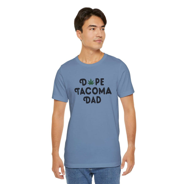 Man wearing a blue "Dope Tacoma Dad" tee with marijuana leaf design, perfect for stylish dads embracing the Tacoma vibe.