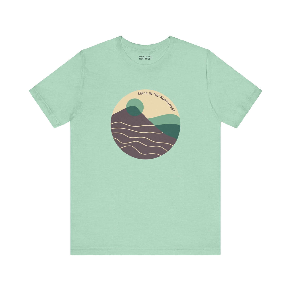 Pacific Peaks Modern Circle Soft Tee with mountain design in muted colors on light green background, inspired by the Pacific Northwest.