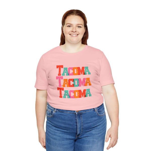 Woman wearing pink Tacoma Trio Soft Tee with colorful block letters