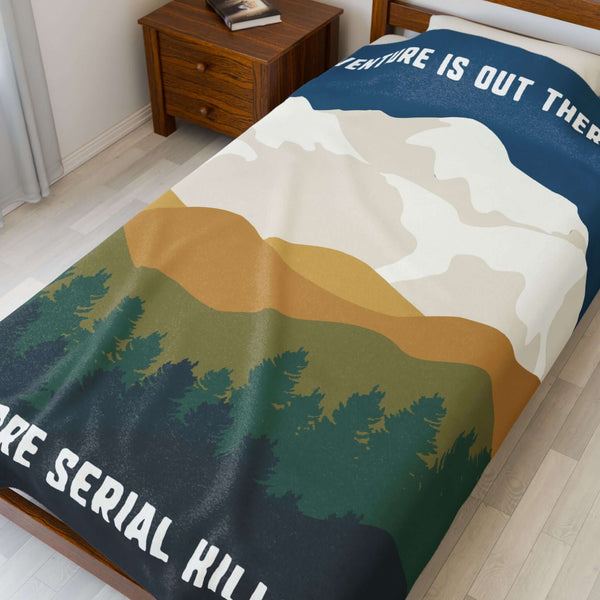 Adventure Is Out There and So Are Serial Killers Lightweight Cozy Blanket spread across a bed with mountain and forest design.
