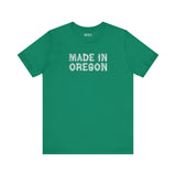 Green tee featuring rustic 'Made in Oregon' log font, perfect for outdoor lovers and Pacific Northwest pride.