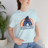 Woman wearing a light blue tee with a Sasquatch graphic and rainbow design, promoting local pride and vintage style.