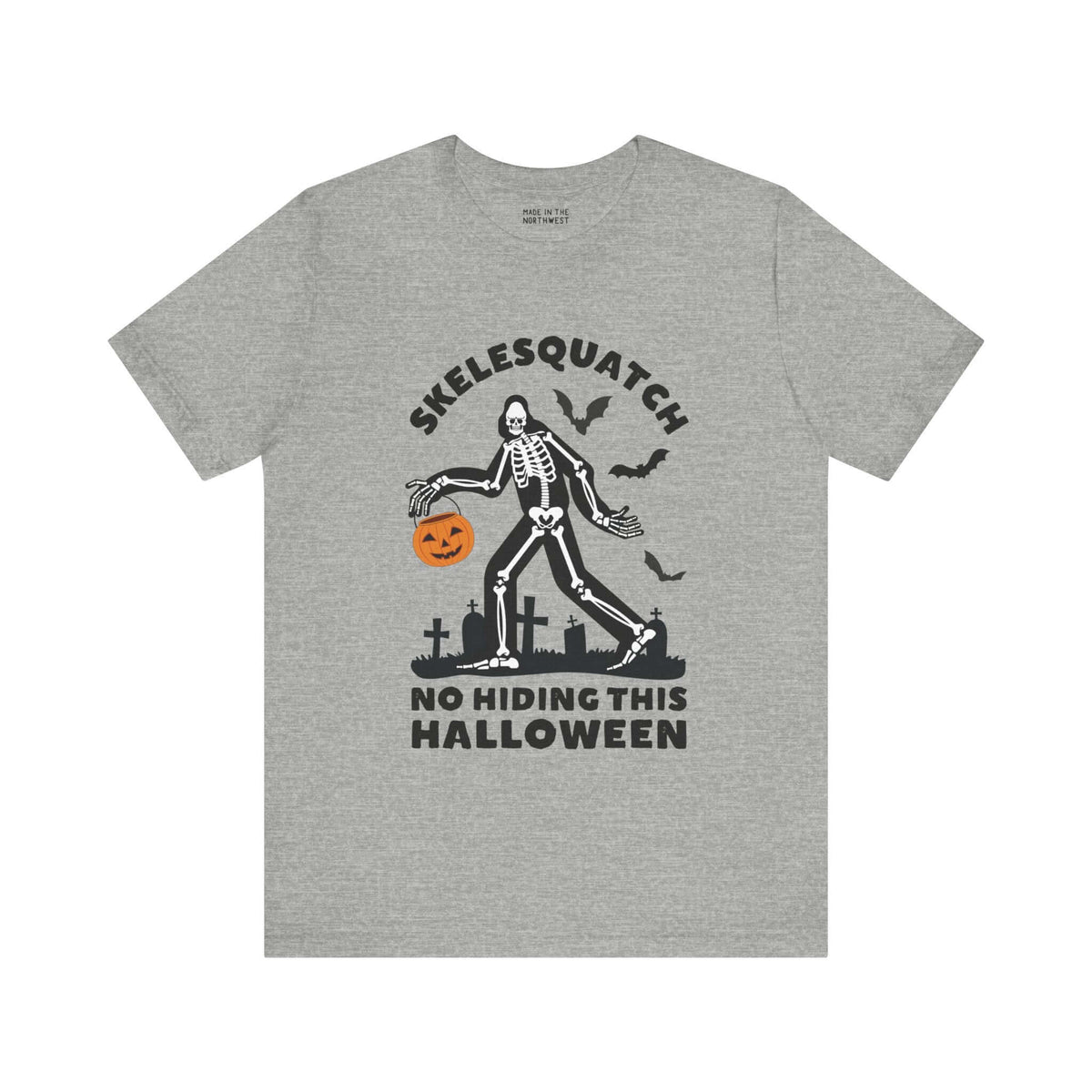 Skelesquatch Halloween tee featuring skeleton Sasquatch with a pumpkin bucket in a graveyard setting, spooky and fun design.