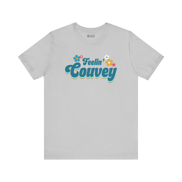 Feelin' Couvey retro tee featuring playful 70s font and colorful flowers on a light gray shirt.