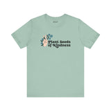 Mint green tee with 'Plant Seeds of Kindness' text and a hand peace sign surrounded by flowers.