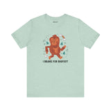 Light green tee with a playful Bigfoot graphic and the text 'I Brake for Bigfoot', celebrating local folklore.