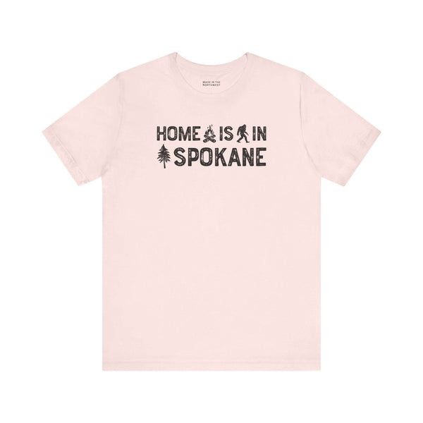 Home Is in Spokane Tee featuring campfire, Bigfoot, and tree illustrations representing Spokane pride.