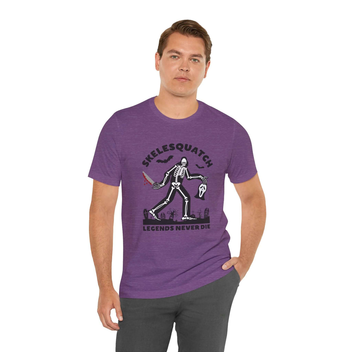 Man wearing purple Skelesquatch 'Legends Never Die' Halloween tee with skeleton sasquatch design and graveyard background.