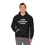 Man wearing a black 'Chill Portland Mom' hoodie, showcasing a stylish and comfortable design for Portland enthusiasts.
