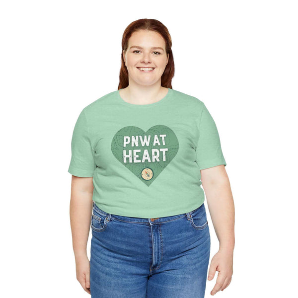 Woman wearing a PNW at Heart Compass Soft Tee with a green heart design, expressing love for the Pacific Northwest.