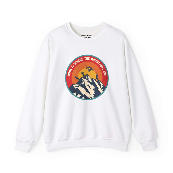 White sweatshirt with 'Home is Where the Mountains Are' design, featuring mountains, hiking, motocross, and Bigfoot in a colorful circle.