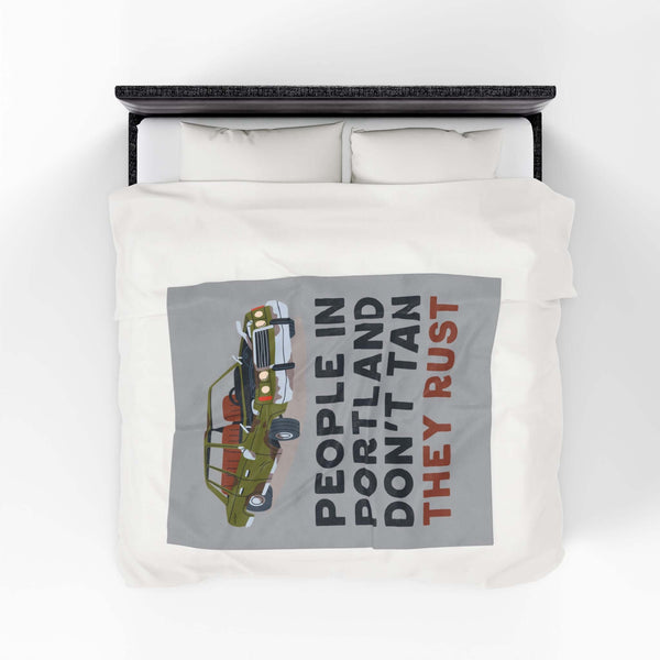 People in Portland Don't Tan They Rust Lightweight Cozy Blanket displayed on a bed with vintage car design.