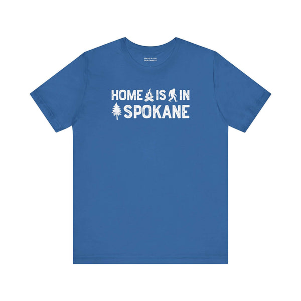 Home Is in Spokane Tee with blue background featuring adventurous symbols of the region.
