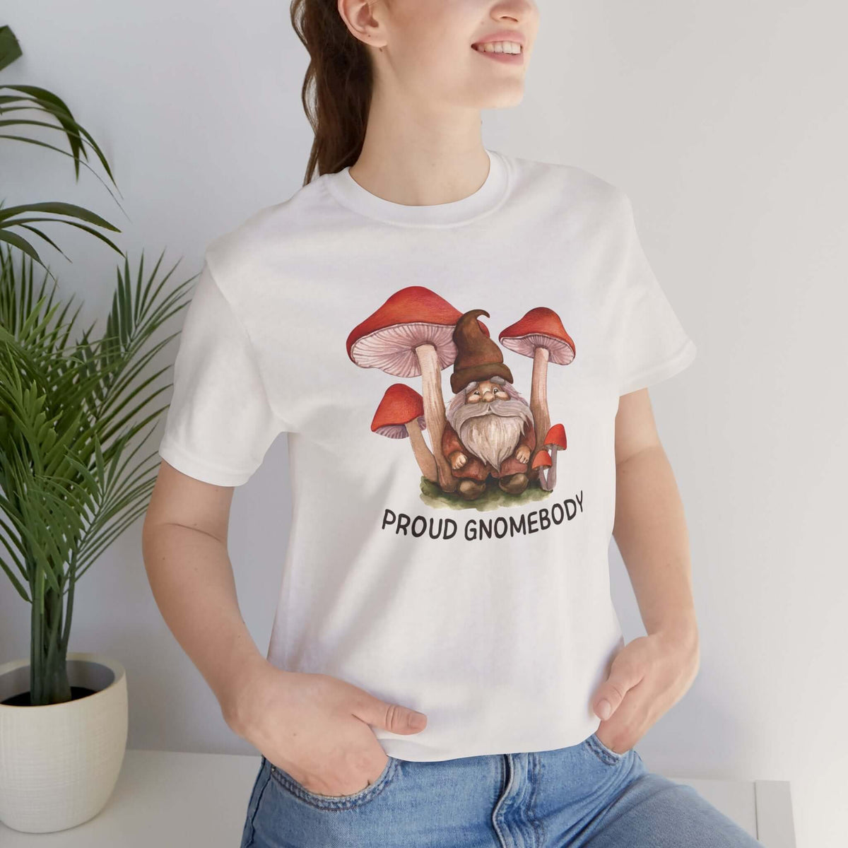 Woman wearing a Proud Gnomebody tee with gnome and mushrooms design, perfect for cozy home vibes.