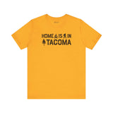 Home is in Tacoma tee featuring campfire, Bigfoot, and tree graphics on a yellow shirt.