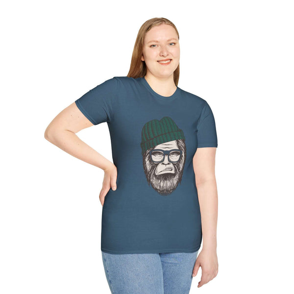 Model wearing Hipster Squatch unisex t-shirt featuring Bigfoot in a beanie and glasses on a blue background.