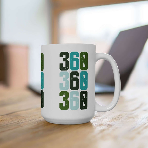Three-Six-Oh Pop ceramic mug showcasing bold green and blue 360 design on a wooden table with a blurred background.