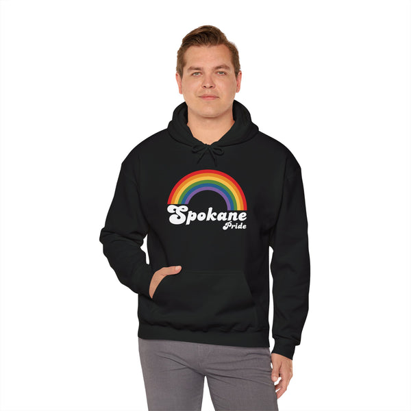 Man wearing a black Spokane Pride cozy hoodie featuring a colorful rainbow design.