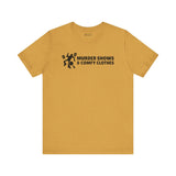 Murder Shows & Comfy Clothes T Shirt in mustard color with playful graphic and bold text.