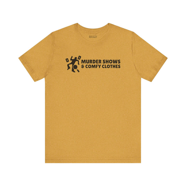 Murder Shows & Comfy Clothes T Shirt in mustard color with playful graphic and bold text.
