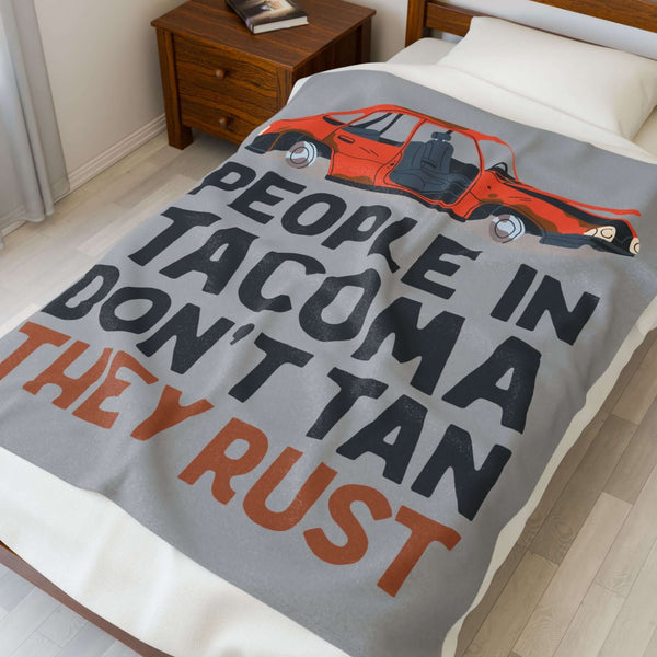 People in Tacoma Don't Tan They Rust Lightweight Cozy Blanket on a bed with a weathered car design.