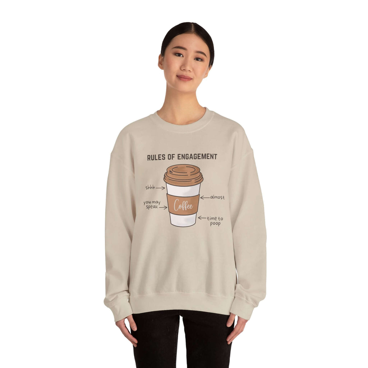 Woman wearing a "Rules of Engagement: Coffee Edition" sweatshirt with a printed coffee cup design and humorous coffee-related text.