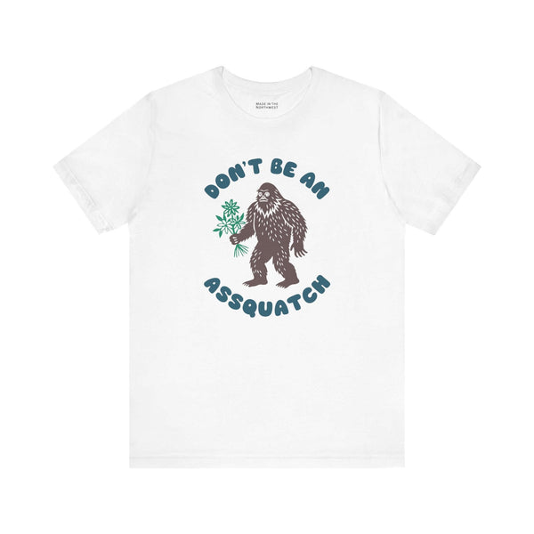 Don’t Be an Assquatch Tee featuring a friendly Bigfoot holding flowers on a white shirt.