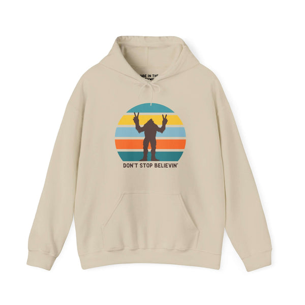 Beige "Don't Stop Believin'" Bigfoot hoodie featuring colorful stripes and playful Bigfoot graphic. Perfect for adventure lovers.