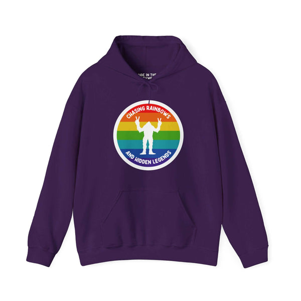 Purple hoodie with rainbow circle and Sasquatch graphic, text reads "Chasing Rainbows and Hidden Legends," celebrating PNW spirit.