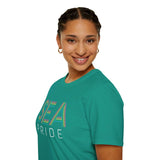 Person smiling in a green SEA Pride t-shirt showcasing rainbow lettering, celebrating community and identity.
