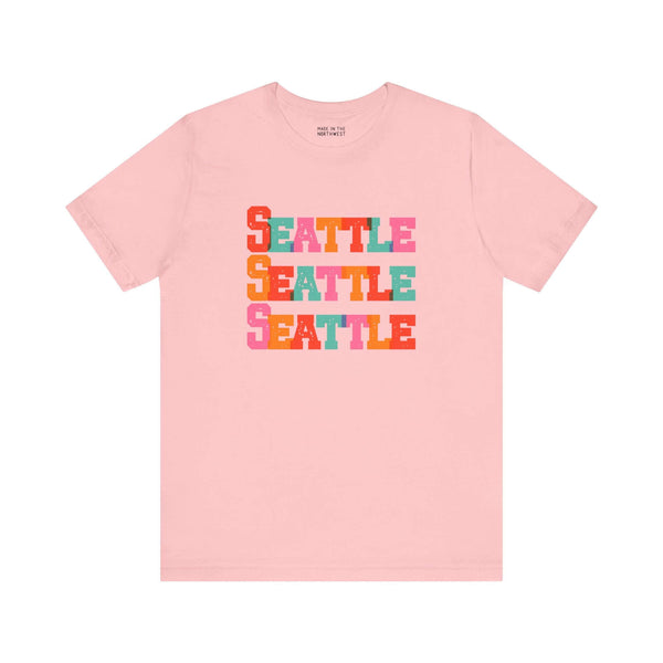 Pink Seattle Trio Soft Tee with colorful stacked block-letter design, perfect for adding a vibrant touch to your wardrobe.