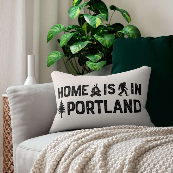 Home is in Portland Lumbar Accent Pillow on a couch with plants, featuring campfire and Bigfoot designs.