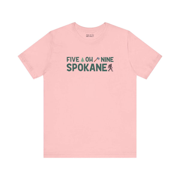 Pink "Five Oh Nine Spokane" tee with axe and tree design, celebrating Spokane pride and local charm.