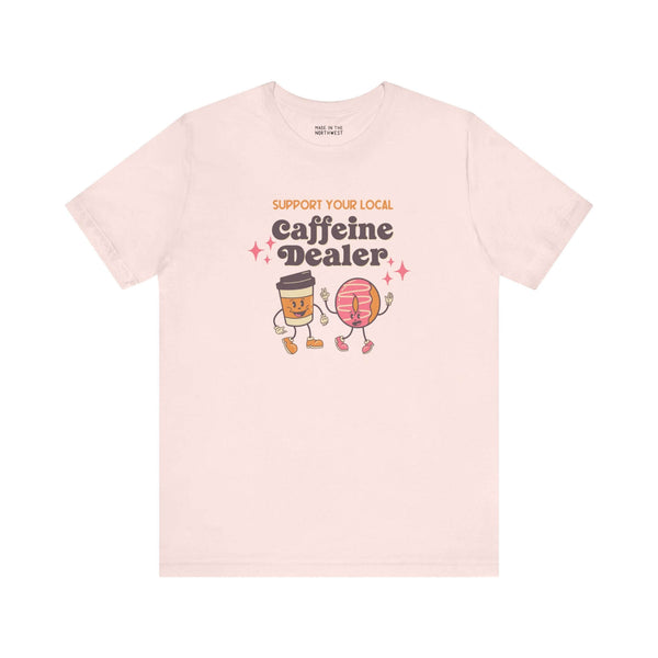 Support Your Local Caffeine Dealer coffee soft tee featuring playful coffee and donut characters on light background.