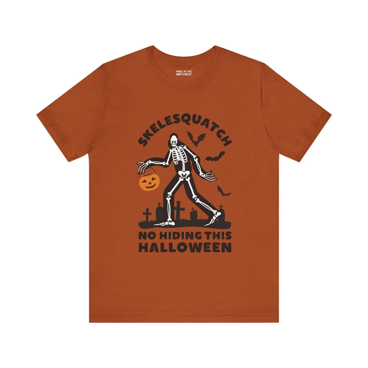 Halloween orange tee with Skelesquatch design, skeleton Sasquatch with pumpkin bucket, graveyard scene, bats and text "No Hiding This Halloween".