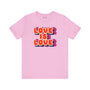 Love Is Love T Shirt featuring retro colorful lettering on a pink background, celebrating pride and positivity.