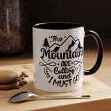 The Mountains Are Calling and I Must Go Mug on a wooden surface with a spoon and macaroon, perfect for coffee lovers.