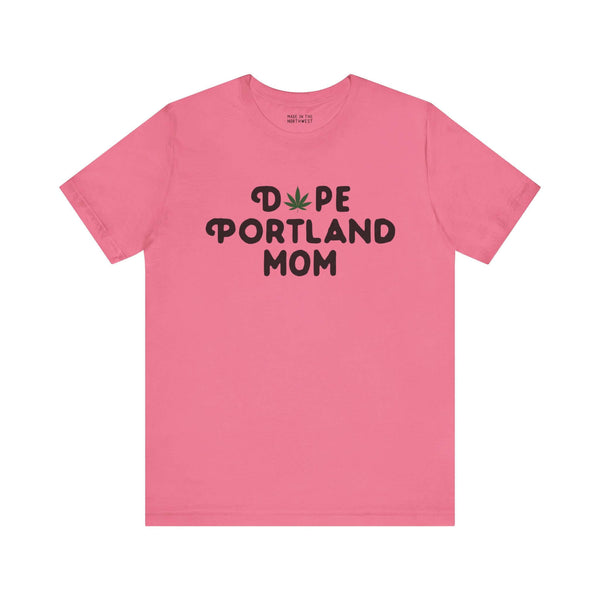 Pink tee with "Dope Portland Mom" text, featuring marijuana leaf design replacing the "O" in "Dope", celebrating Portland's vibrant spirit.