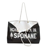 Home is in Spokane Weekender Bag featuring a graphic with a campfire, sasquatch, and trees.