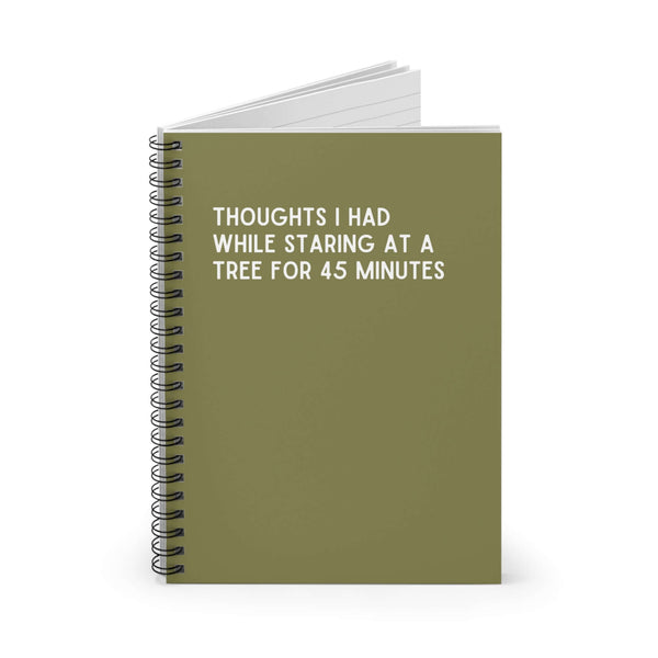 Spiral notebook with green cover titled 'Thoughts I Had While Staring at a Tree for 45 Minutes' for creative writing.