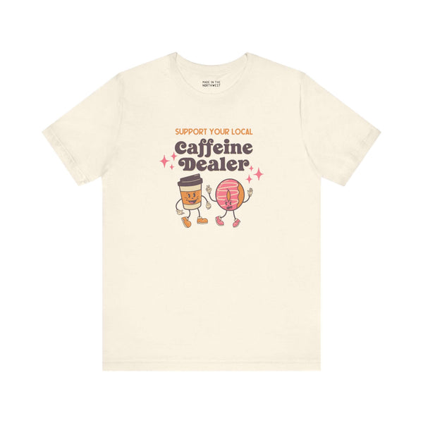 Playful Support Your Local Caffeine Dealer coffee soft tee featuring cartoon coffee cup and pastry.