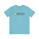 Light blue tee with 'Made in the Northwest' logo and compass design, showcasing Pacific Northwest pride for adventurers and explorers.